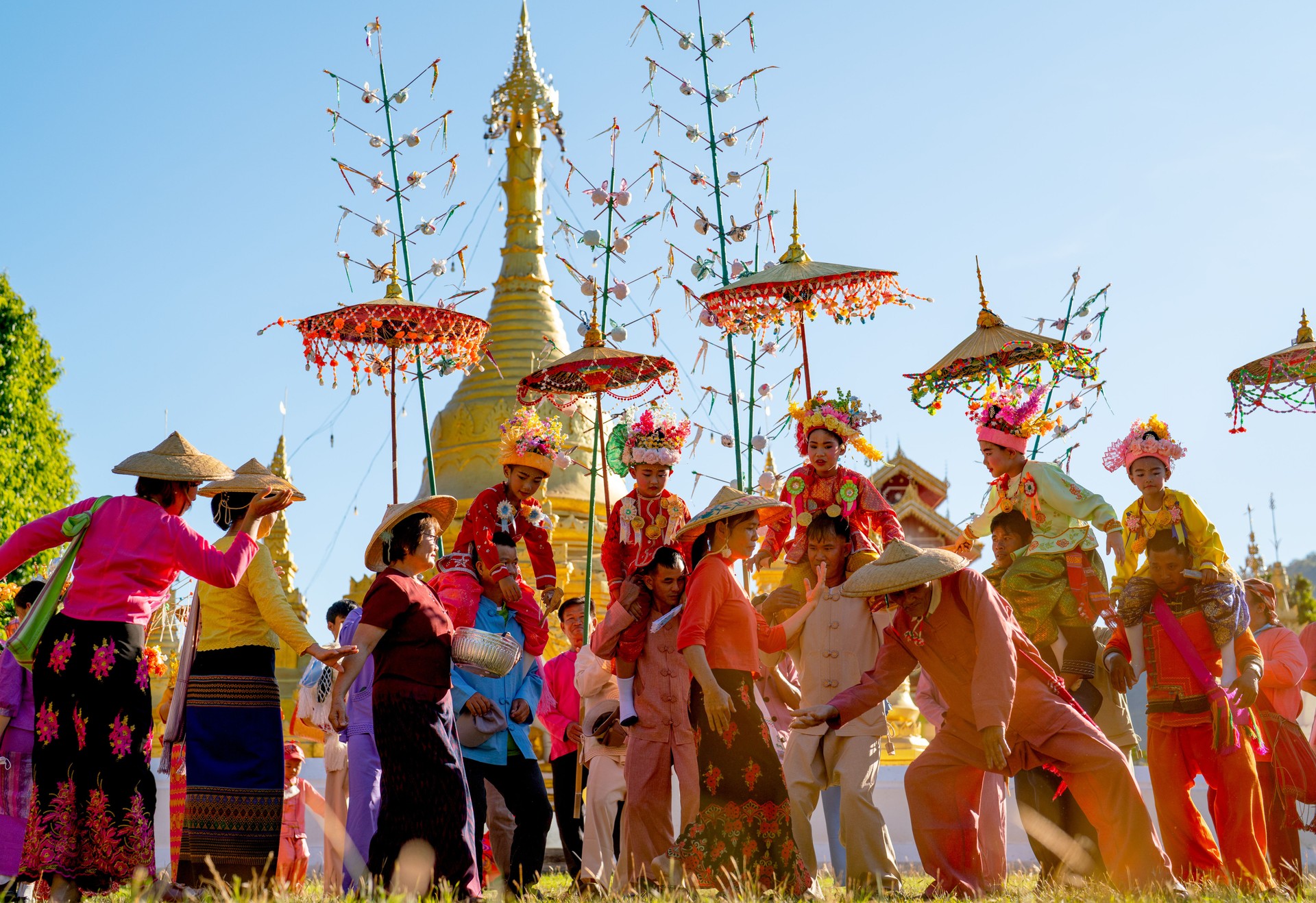 Group of Aisan people celebrate and enjoy dancing with Poy Sang Long Thai northern tradditional activities in front of golden pagoda in area of temple.